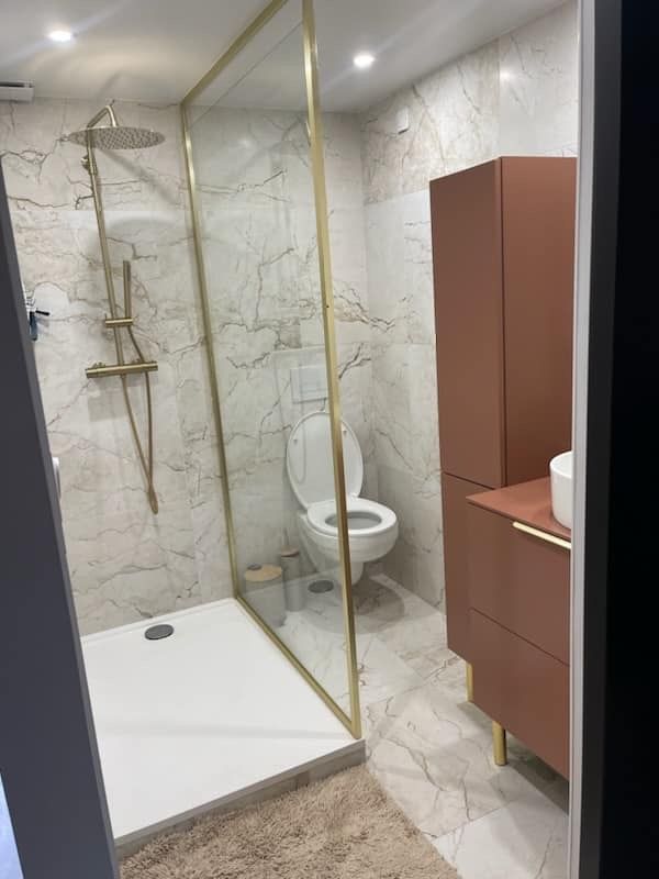 Salle de bain en marbre avec douche et paroi dorée